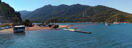 Bus, sea, sky, boats and tourists in water at Girl Sand Beach in Turkey. Famous shoal, a place of pilgrimage of tourists you can to ford cross hundreds of meters from one shore to another. Panoramaの写真素材