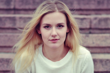 Portrait of a blond girl in a white sweater.の写真素材