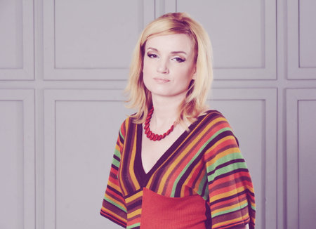 Beautiful girl posing in studio. She is dressed in a striped knitted blouse and white jeans. Clothing in the style of the 1970s.の写真素材