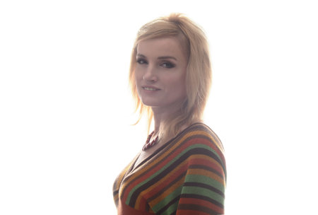 Studio portrait of a beautiful blonde girl. She is dressed in a knitted blouse in a strip, on her neck she has a beautiful necklace. Clothing in the style of the 1970s. A clean white background.の写真素材