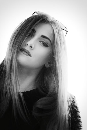 Portrait (face) of a young woman, natural look, street photo, long hair overlap one eye, glasses on the head, make-up, leather jacket, youth, beauty, easeの写真素材