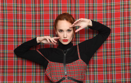 Creative experiments in fashion: a girl in a plaid dress poses against a background of fabric of the...