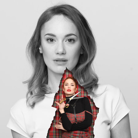 An initiative cheerful girl in a plaid dress breaks a hole in her large black and white boring photograph. Modern fashion concept: you have the right to be yourself.の写真素材