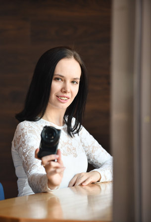 Young brunette woman, novice photographer, with modern compact digital camera takes pichures