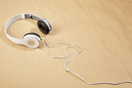 white headphones with black inserts and a white cord lie on a surface of Kraft paperの写真素材