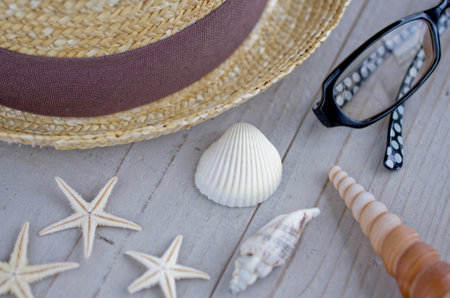 straw hat, sunglasses, starfish and seashell on white boardの写真素材