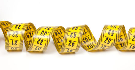 A coiled yellow measuring tape isolated on white