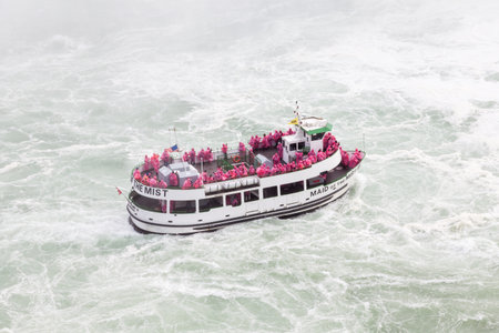 Tourist boat Maid of the Mist beside the Horseshoe Falls.  The Falls are part of the Niagara Falls bridging the Canadian and American borders.のeditorial素材