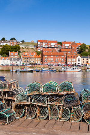 The view across lobster fishing pots stacked on the keyside of the seaside town of Whitby in Yorkshire, Northern England.のeditorial素材