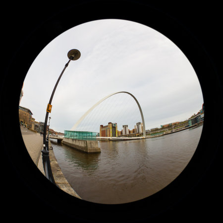 A fish eye view of the Gateshead Millennium Bridge.  The bridge connects Newcastle upon Tyne and Gateshead in north east England.  In the background is the Baltic Centre for Contemporary Art, a converted flour mill on the banks of the River Tyne.のeditorial素材