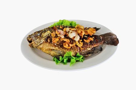 Fried tilapia fish and fried garlic on white plate