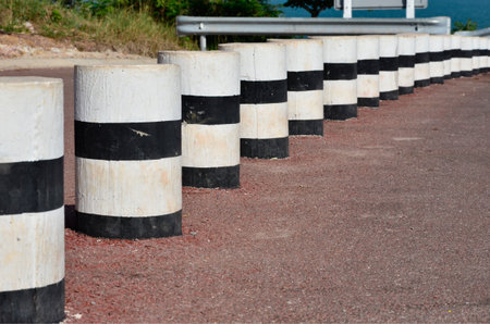 Black and white barriers beside the roadの写真素材