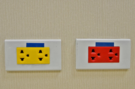 Yellow and red plugs on the wallの写真素材
