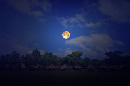 Beautiful full moon over straw hutsの写真素材