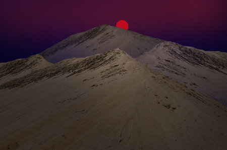 Red sun downs behind sand mountainの写真素材