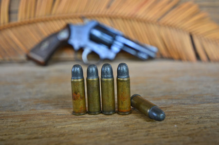 Five old bullets with revolver gun background
