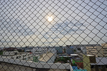 City and sun behind wire net wall