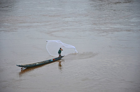 Fisherman hunts fish in the wide riverの写真素材