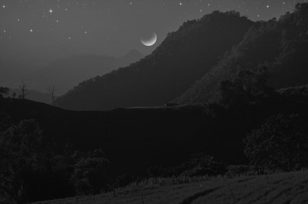 Black and white image of full moon over the mountainの写真素材
