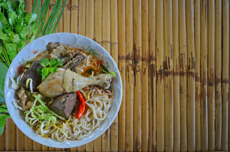 Thai noodles with chicken curry soup on bamboo floorの写真素材