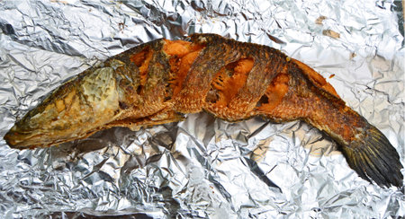 Big yellow fried snakehead fish on clean silver aluminum foilの写真素材
