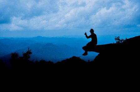 Silhouette picture of man on cliff over the valley