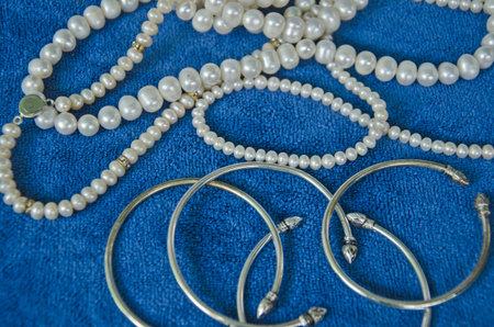 Top view of pearl necklaces and bracelets on blue clothesの写真素材