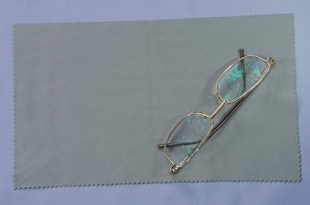 Eyeglasses with golden frame on gray clothes and floor