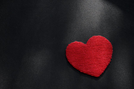 Sunlight drop on red heart on black floorの写真素材