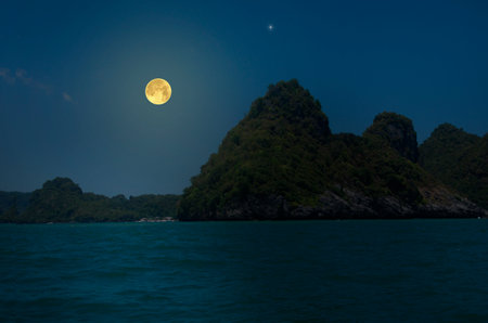 Beautiful full moon over mountains and seaの写真素材