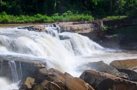 Beautiful bright waterfall on rock cliff in the park in Thailand