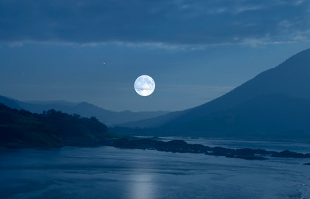 Romantic super white moon over blue mountains and river in the evening of winterの写真素材