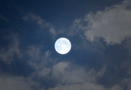 Big bright romantic full moon and clouds in blue sky in the night of summer