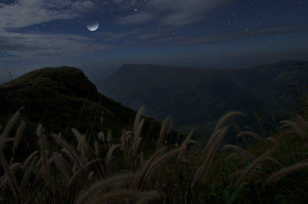 Beautiful wanning moon above the mountains and valley in early morning in summer seasonの写真素材