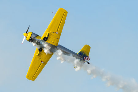 Yellow plane doing turns while sending smoke