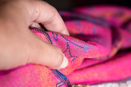 Hand soflty touching a pink cashmere fabric