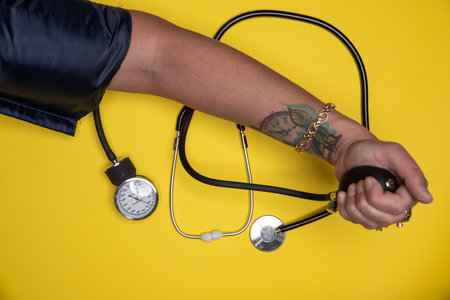 Hand checking blood pressure and stethoscope set asideの写真素材