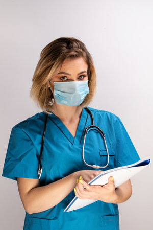 Portrait of young doctor with stethoscope wearing face mask holding paper resultsの写真素材