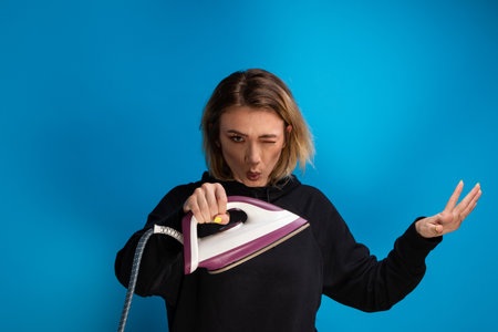 Girl whistling and winking while holding a flatironの写真素材