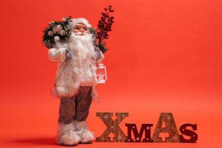 Santa Claus toy standing next to a wooden Xmas text signの写真素材
