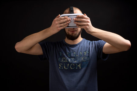 Male using 3d VR gadget is touching device with both handsの写真素材