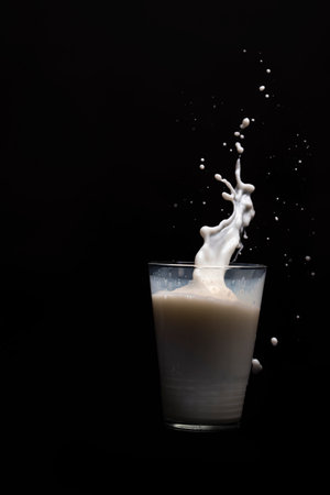 Milk glass splash isolated on black backgroundの写真素材