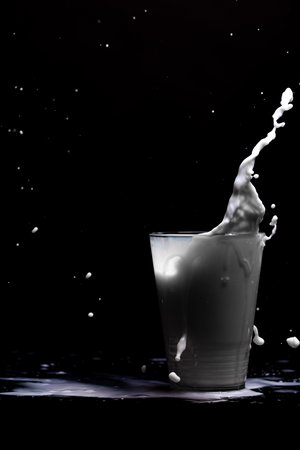 Milk glass splash isolated on black backgroundの写真素材