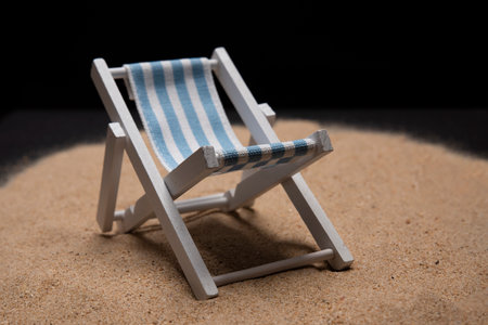 Isolated sunbed toy layed on sand against black background