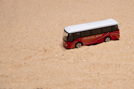 Isolated toy bus on sand with copy space availableの写真素材