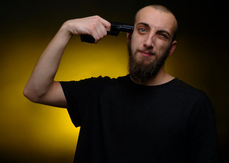 Portrait of a young man pointing a gun to his headの写真素材