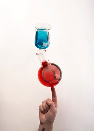Flat bottom flask and a Berzelius beaker glass balanced on top of fingertipの写真素材
