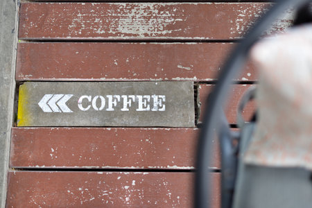 A white coffee sign with a white arrow indicated the entrance door on the wooden floor of the coffee...