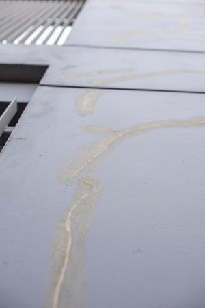 Cracked painted concrete wall on sun set side with marks of old stain glue fixing on exterior modern...