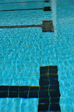 A swimming pool with a sunny reflection and beautiful wavy water surface in turquoise blue color.